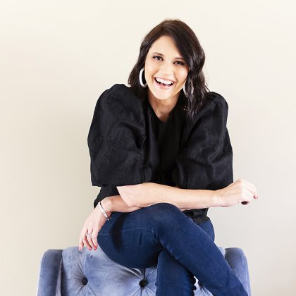 Photo of Sharlene Allsopp sitting on top of a purple-coloured armchair with her arms crossed across her crossed legs